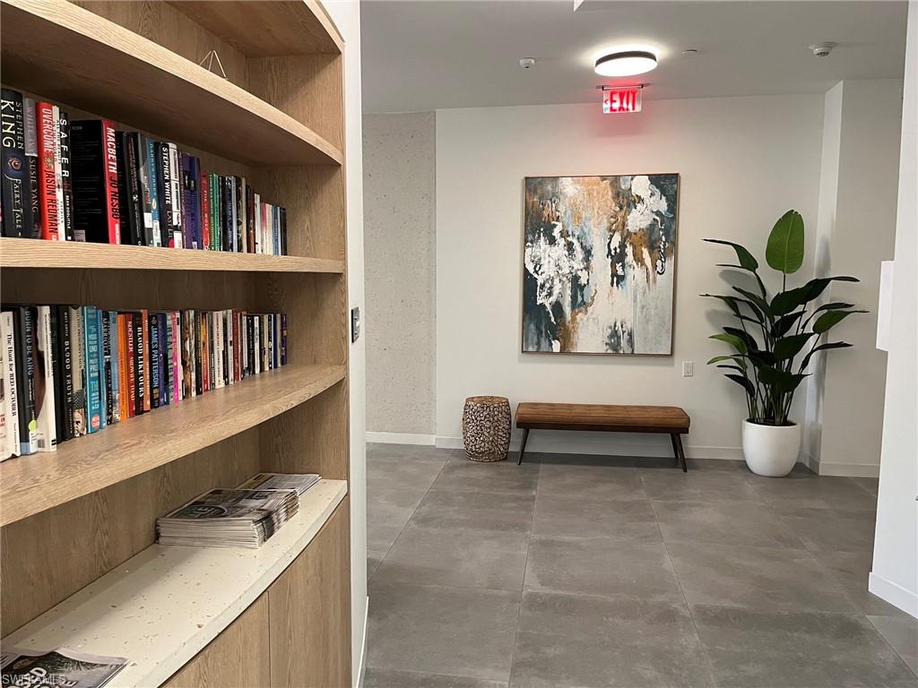 Built-in wood-finish shelving with integrated countertop, large format tile flooring, and recessed ceiling lighting