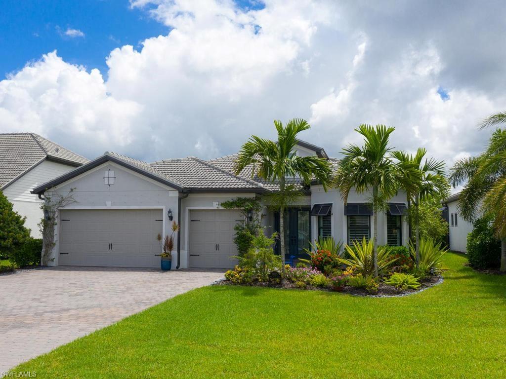 Stucco exterior with a tiled roof, 3-car garage, and a paver driveway