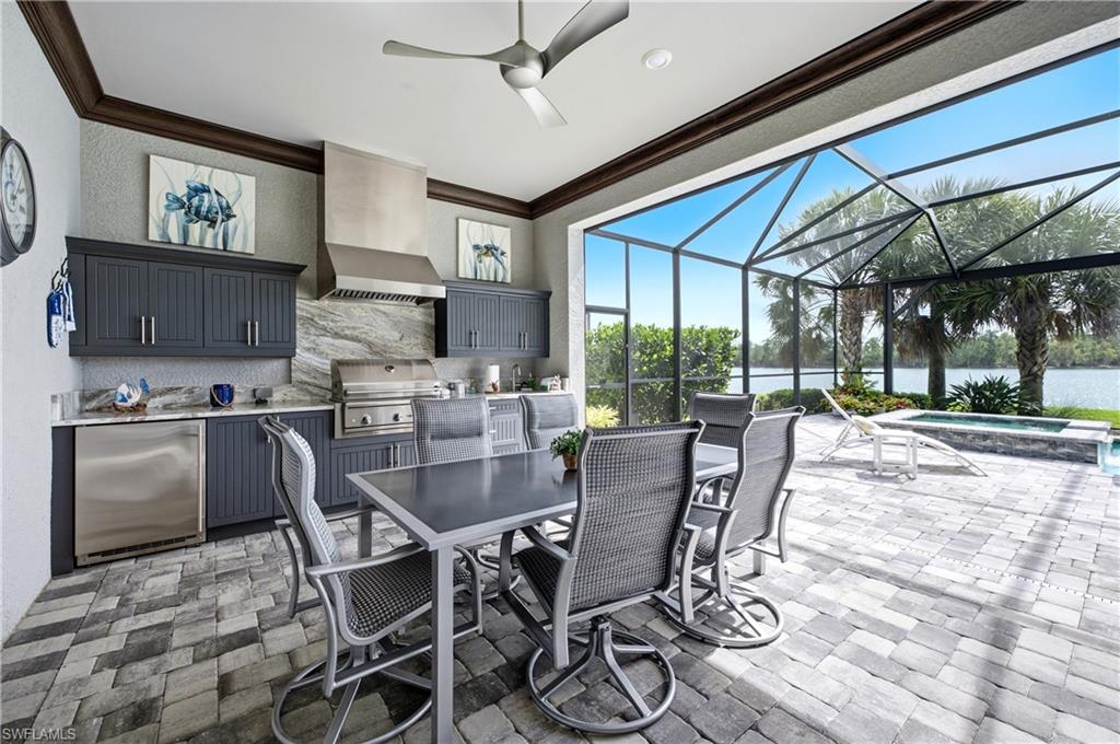 Screened outdoor living area featuring a built-in kitchen with stainless steel appliances