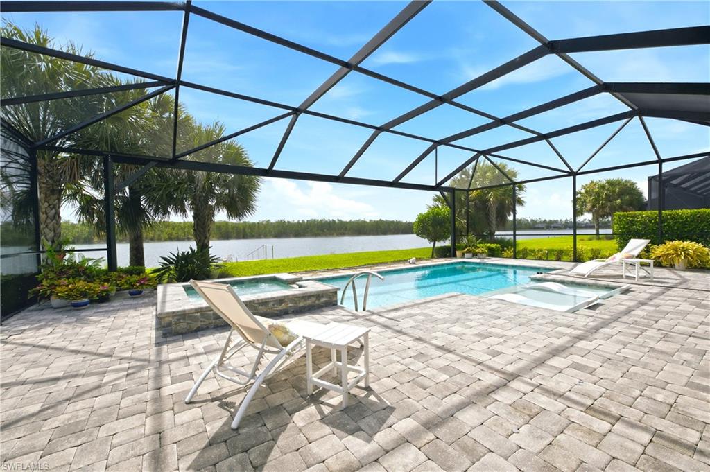 Screened outdoor living area featuring  salt-water pool, integrated spa, and expansive paver patio