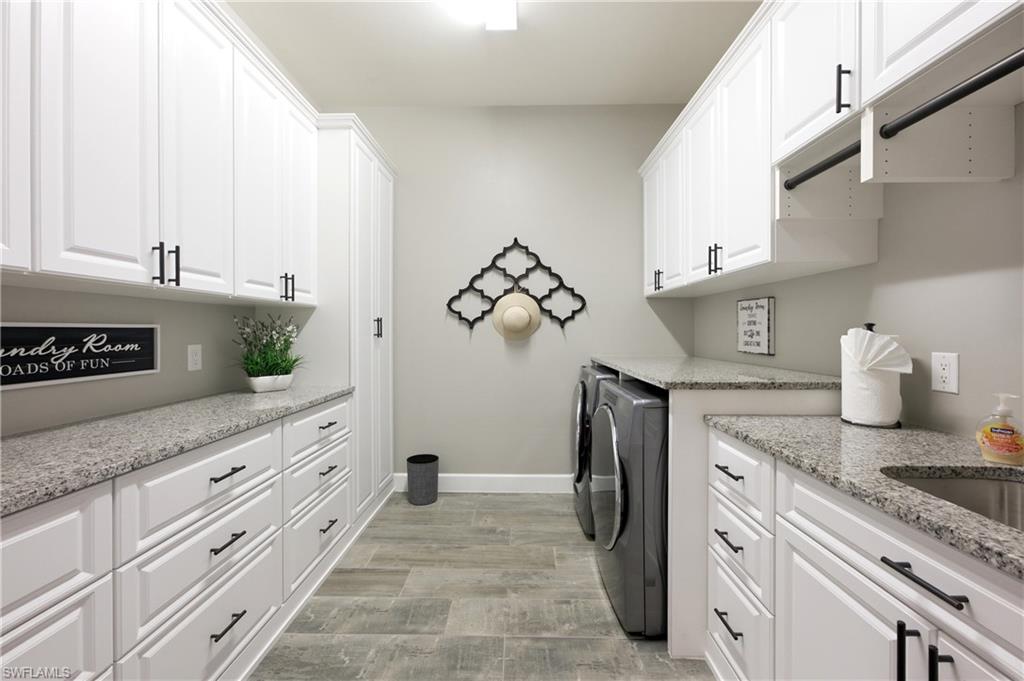 Laundry area featuring white cabinetry, granite countertops, tile flooring, and a built-in sink