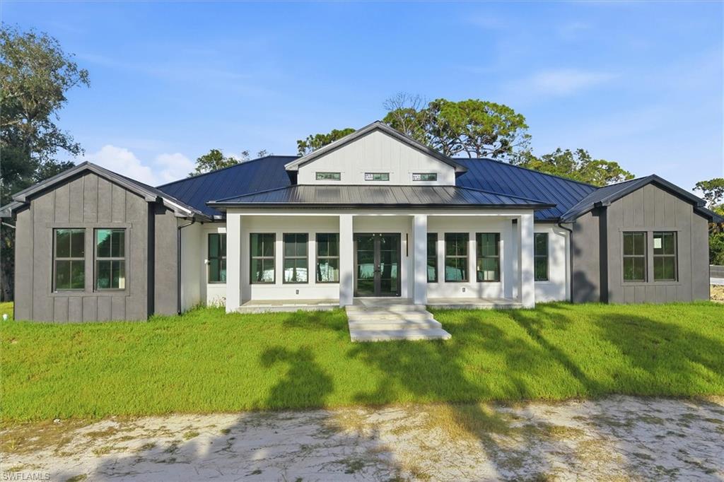 Modern farmhouse residence showcasing a symmetrical facade with board-and-batten siding, a prominent gabled roofline with dark asphalt shingles, and expansive multi-pane windows