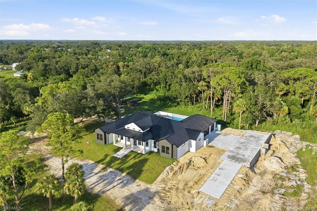 Modern residence with a striking dark exterior and clean-lined architecture, set on expansive grounds featuring mature landscaping and established trees