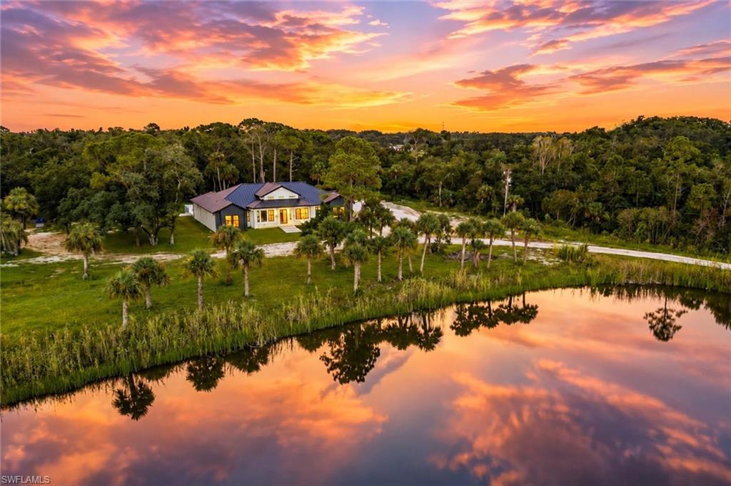 Waterfront residence set on expansive grounds featuring mature landscaping, native palmettos, and manicured lawn with direct water frontage