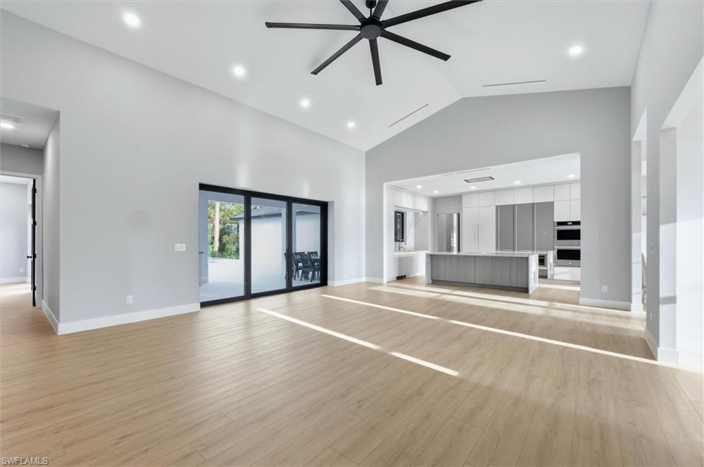 Open-concept living space featuring light wood-finish flooring throughout, recessed ceiling lighting, and a modern ceiling fan