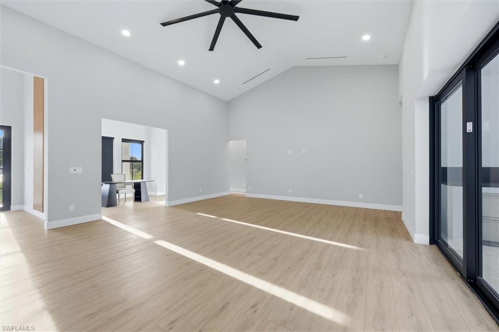 Spacious open-concept living area featuring light wood-finish flooring throughout, recessed ceiling lighting, and a contemporary ceiling fan