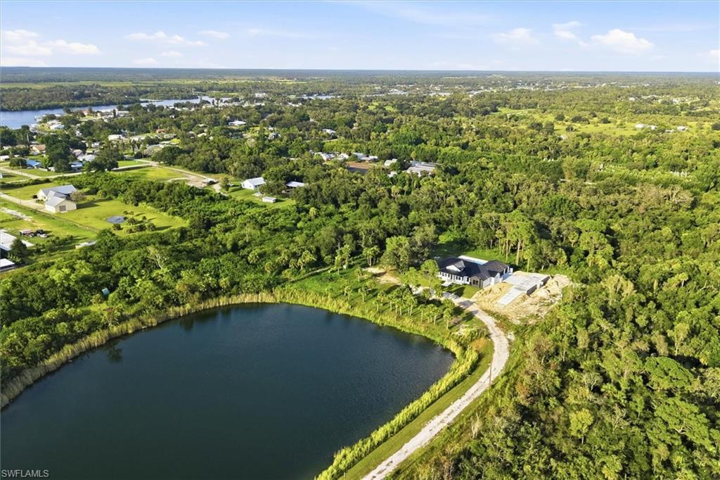 Pristine lakefront property offering a private circular lake surrounded by mature hardwood forest, a manicured lawn, and a gated entry drive