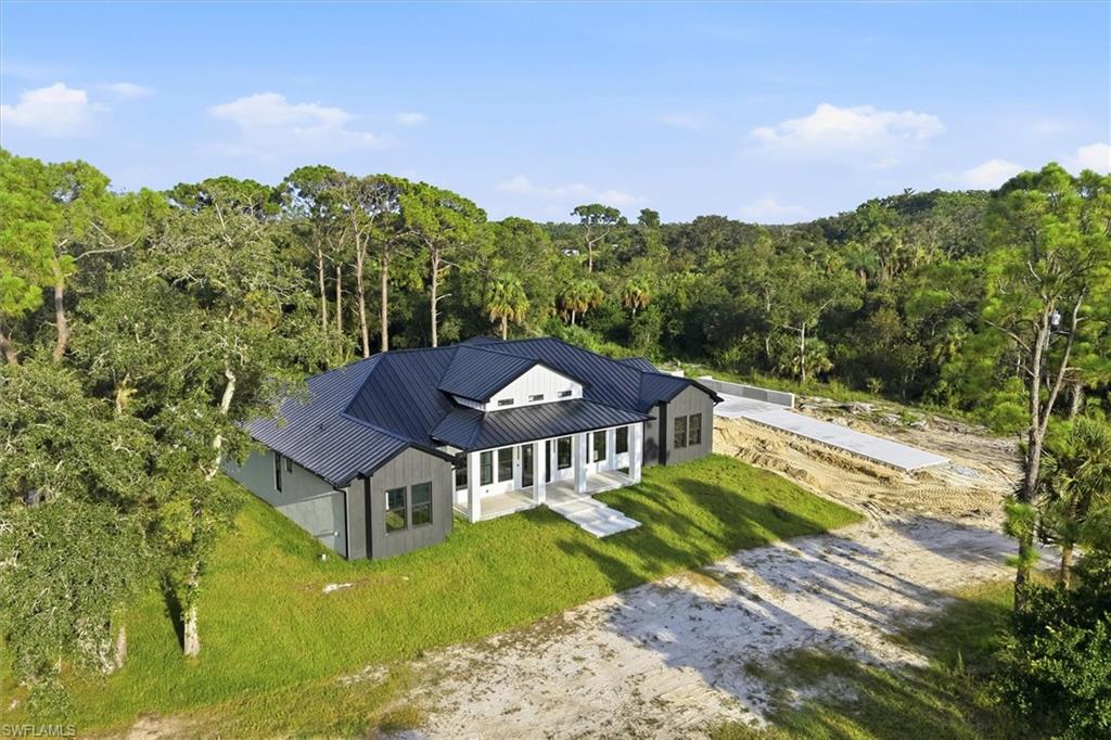 Modern residence featuring a distinctive peaked roofline with dark architectural shingles, white exterior trim, and arched window details