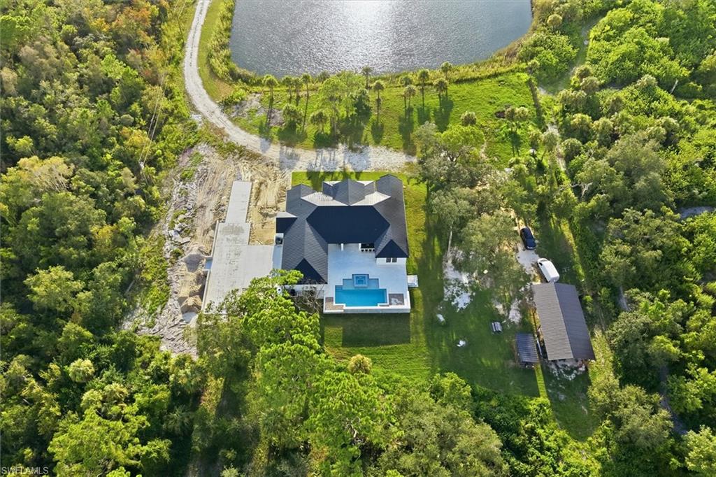 Expansive property featuring a modern residence, dark-tiled roof, and an integrated swimming pool with a surrounding patio
