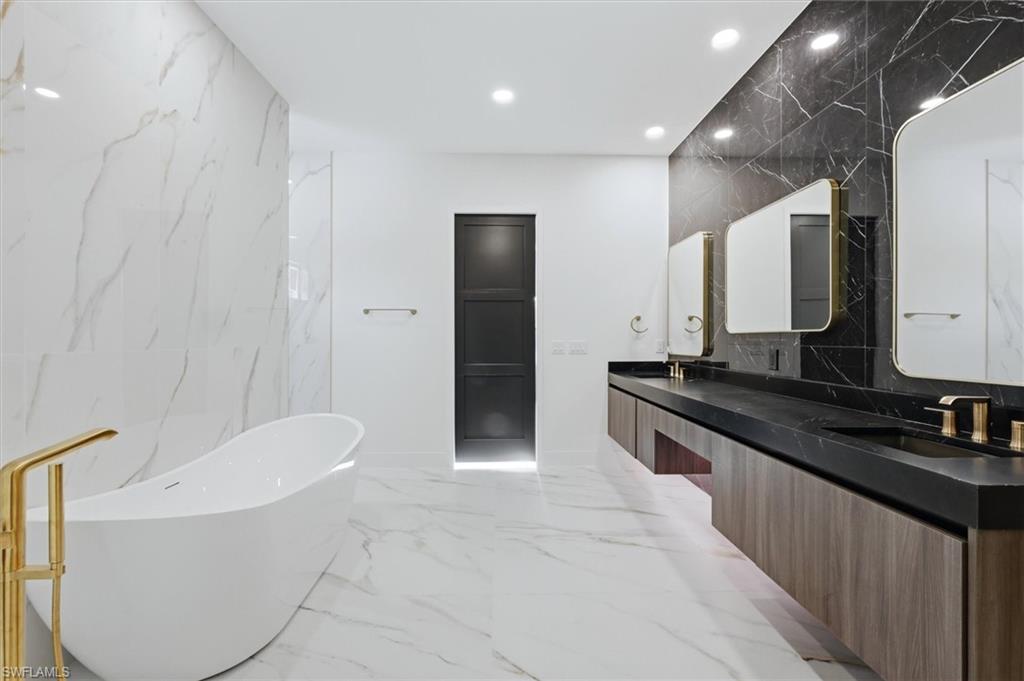 Freestanding soaking tub with a gold-tone floor-mounted faucet