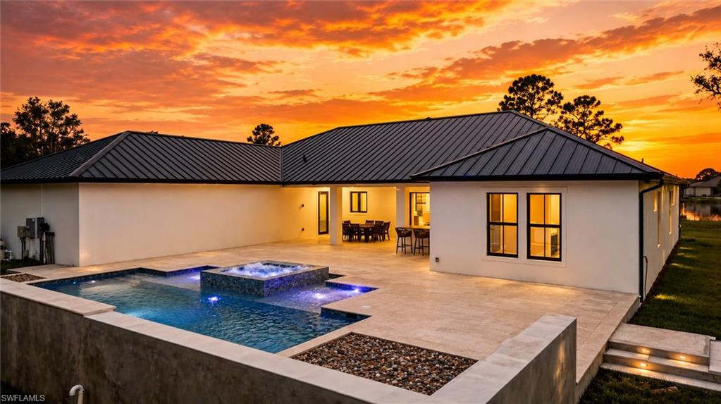 Modern residence showcasing a resort-style backyard with illuminated saltwater pool, integrated spa, and expansive patio