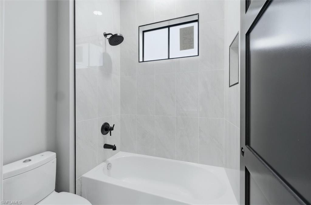 Modern bathroom featuring a frameless glass shower enclosure with matte black fixtures, white subway tile surround, and a soaking tub