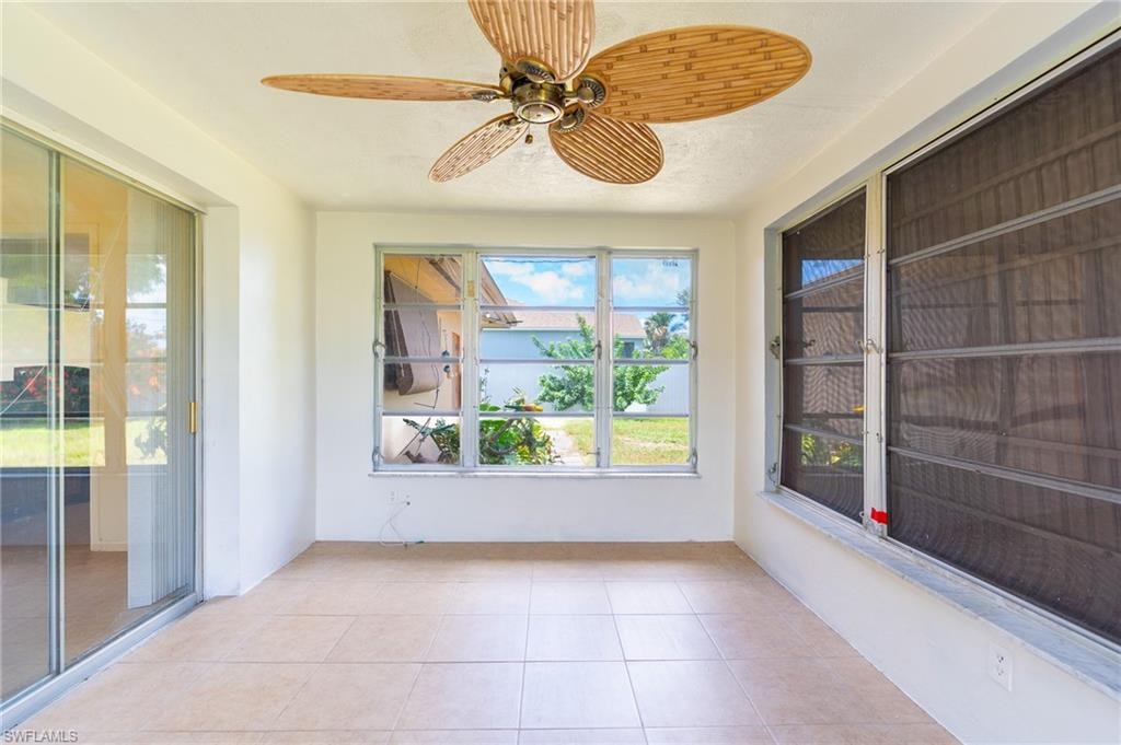 Tiled flooring with a ceiling fan, multiple windows, and a sliding glass door