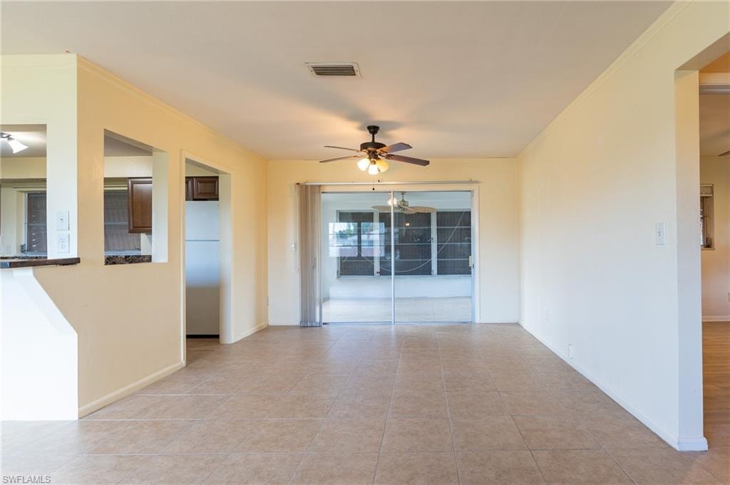 Spacious open-concept living area with ceramic tile flooring, ceiling fan with integrated lighting, and sliding glass doors opening to outdoor space