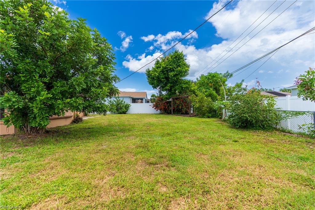 Expansive grassy yard with mature trees and a privacy fence