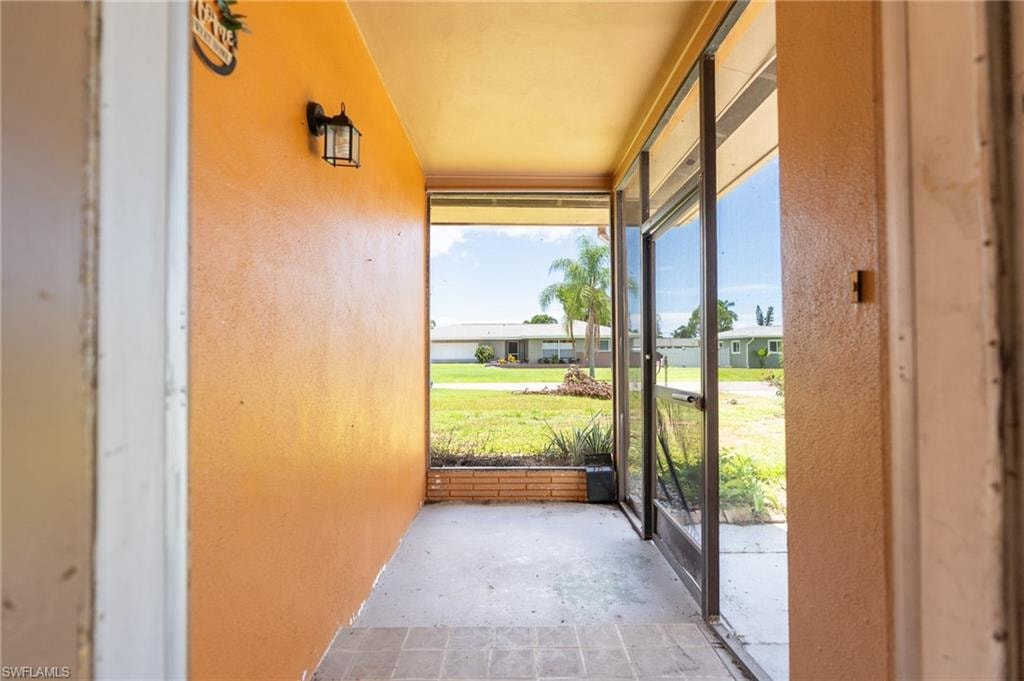 Screened entry porch with a tiled floor, exterior wall sconce, and brick planter box
