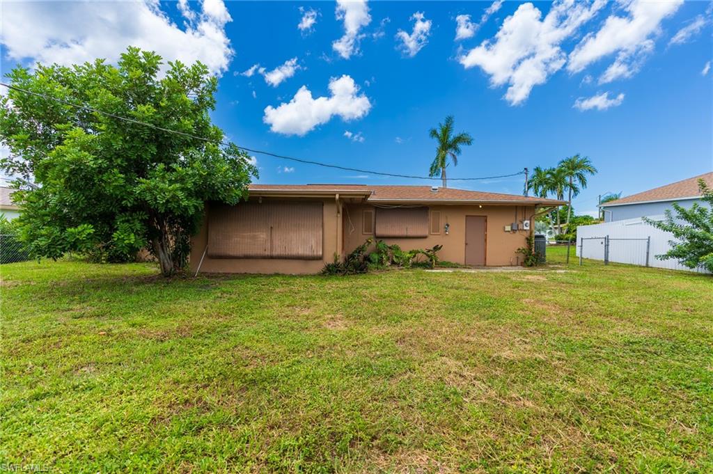 Expansive rear yard featuring green lawn, mature tree, and fencing
