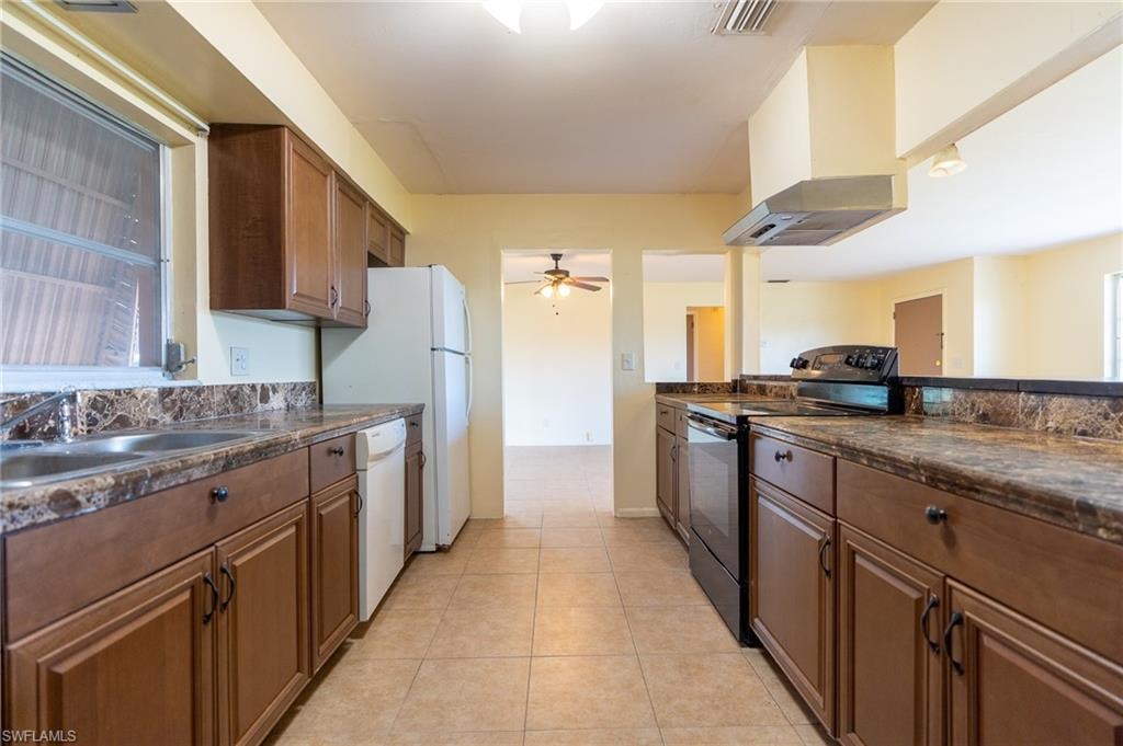 Kitchen featuring wood-finish cabinetry, tile flooring, and a double basin sink