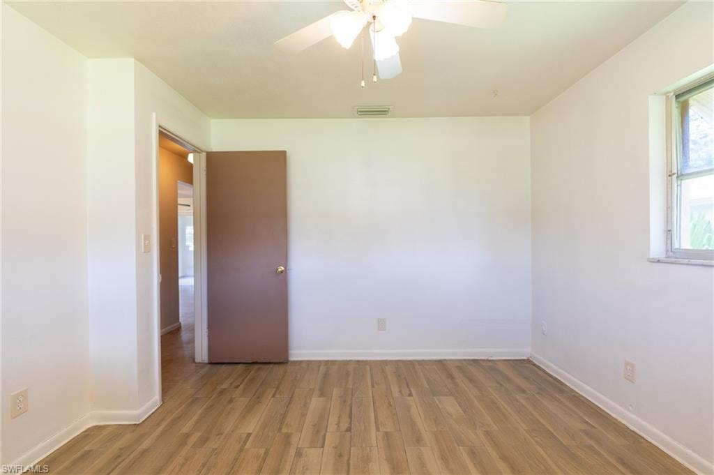 Wood-finish flooring, white walls, ceiling fan, and window