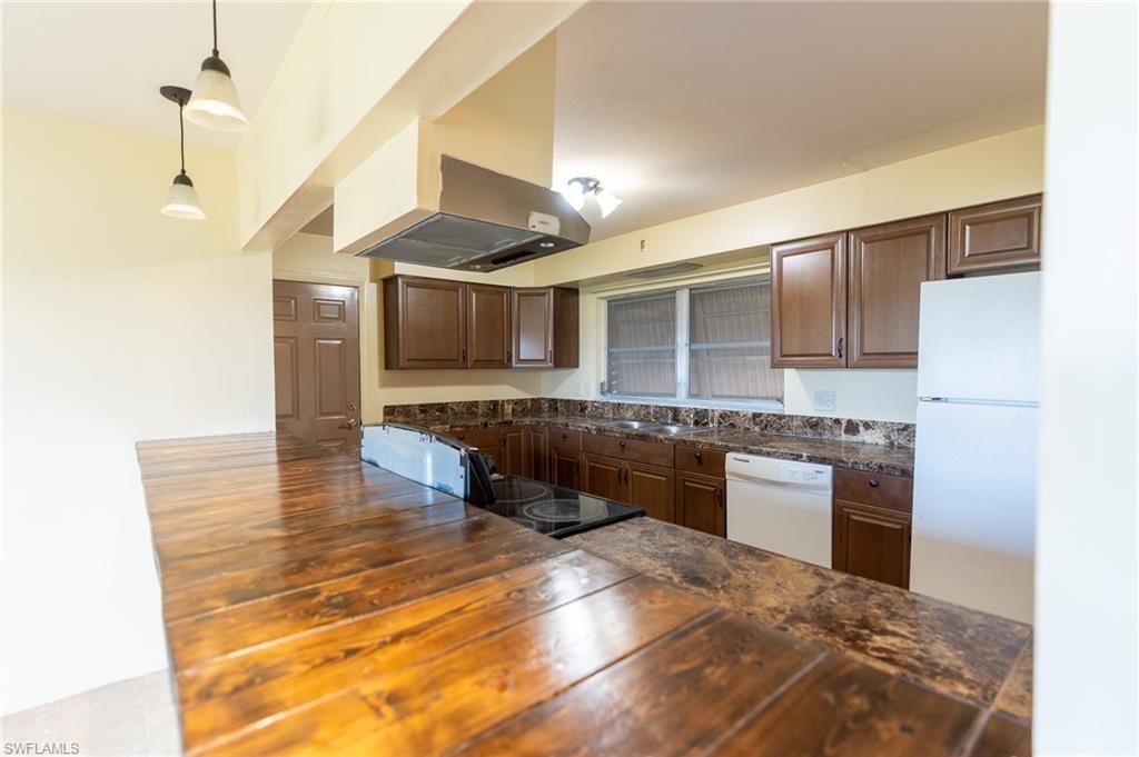 Kitchen with wood-finish breakfast bar, dark wood cabinetry, and stone-look countertops