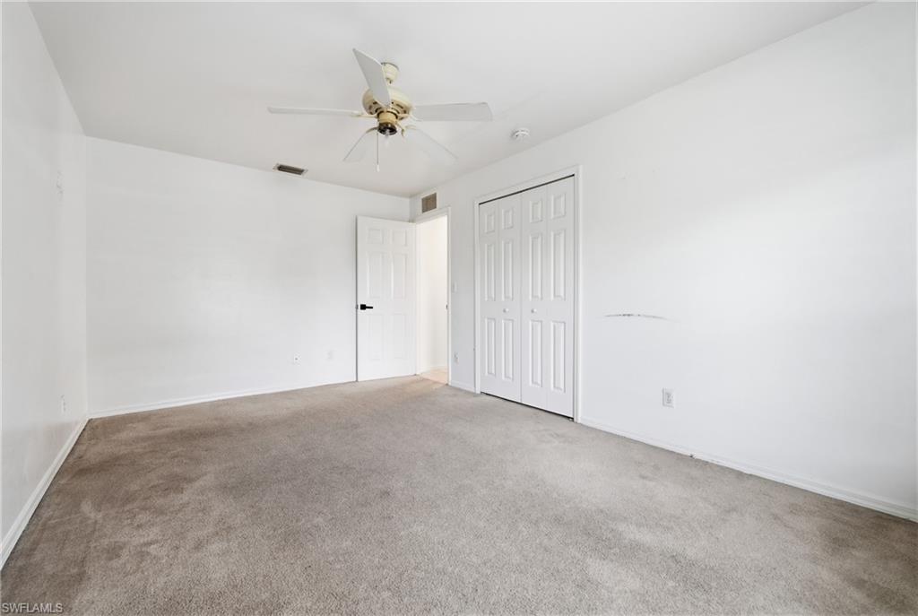 Carpeted room with white walls, a ceiling fan, and bi-fold closet doors