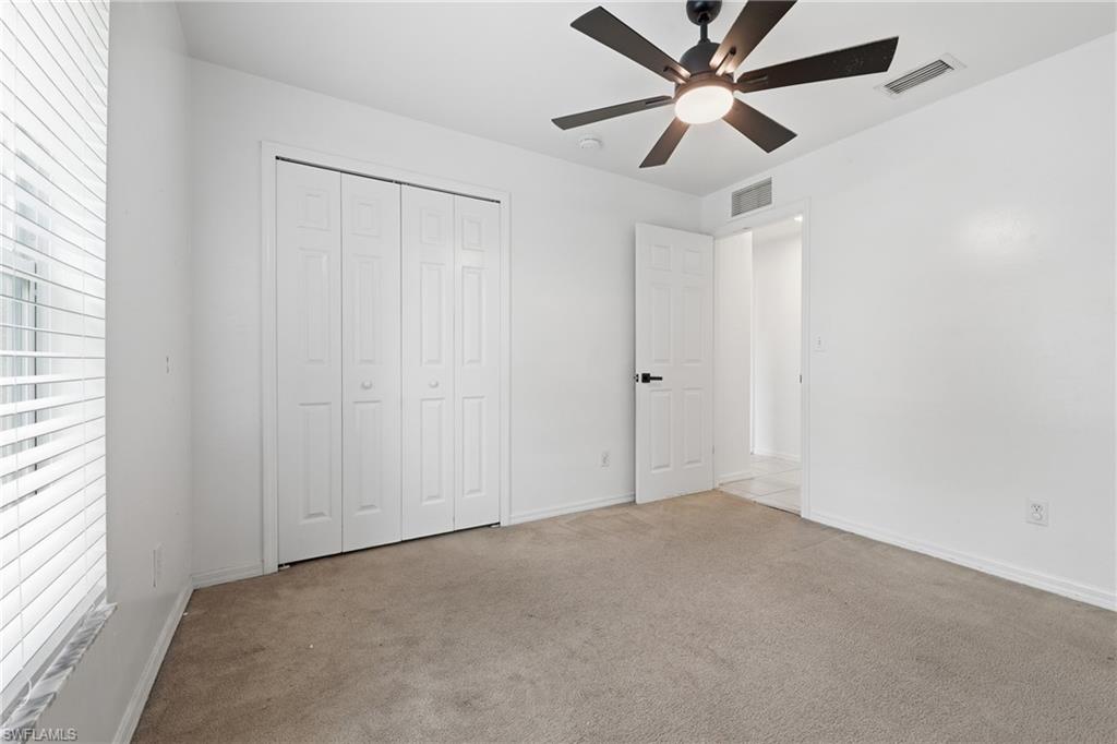 Neutral wall tones, carpeted flooring, window with blinds, bi-fold closet doors, and a ceiling fan with integrated lighting