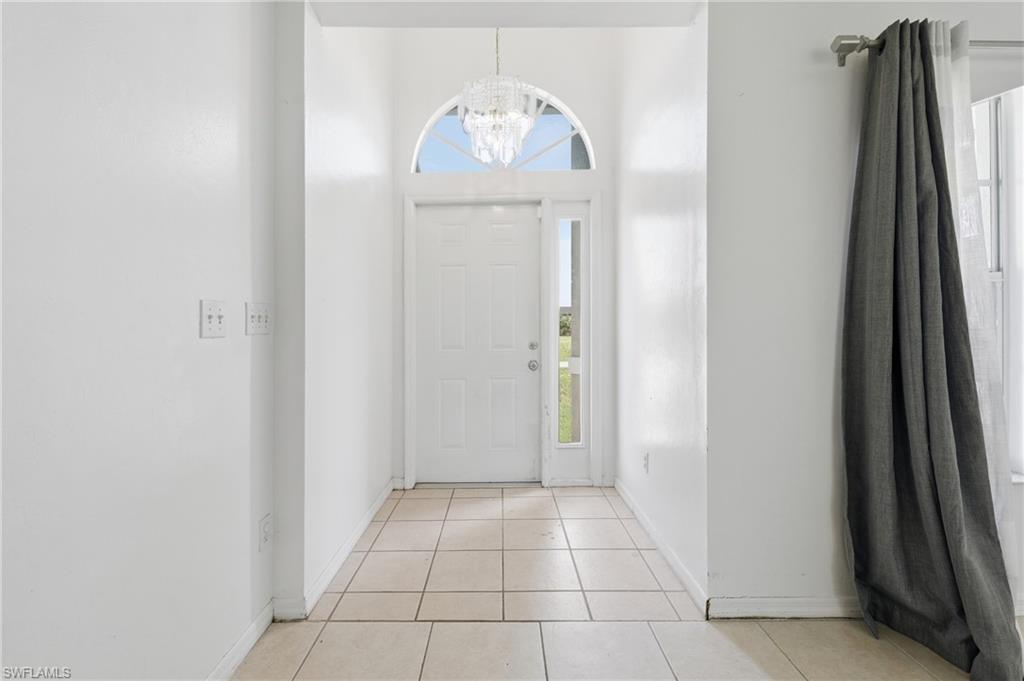 Foyer with tile flooring, a clear paneled entry door, arched transom window, and a decorative overhead light fixture