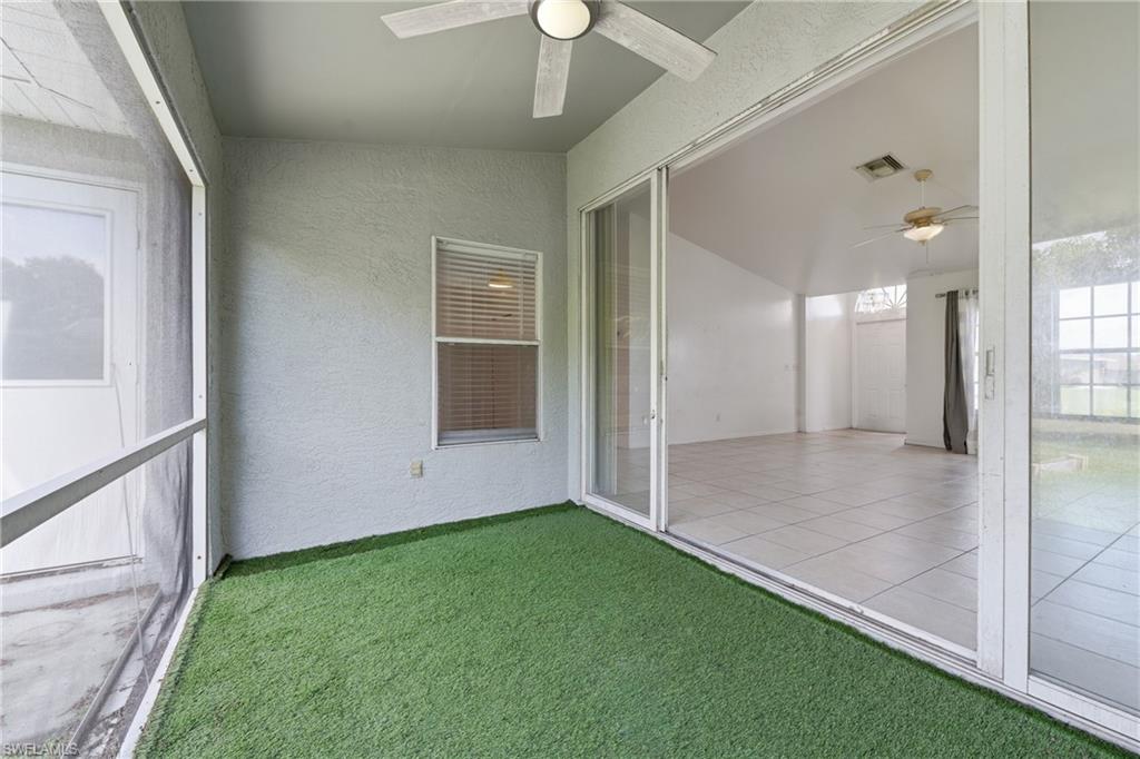 Screened patio featuring artificial turf flooring and a ceiling fan