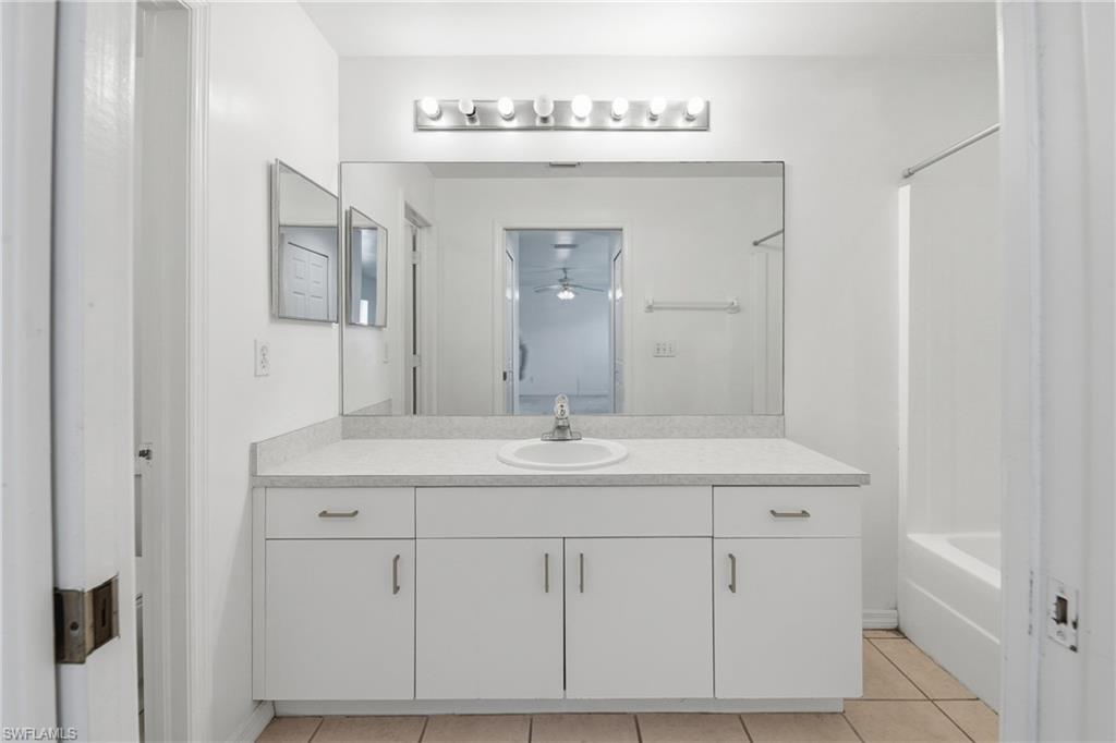White vanity with integrated sink, expansive mirror, and overhead vanity lighting