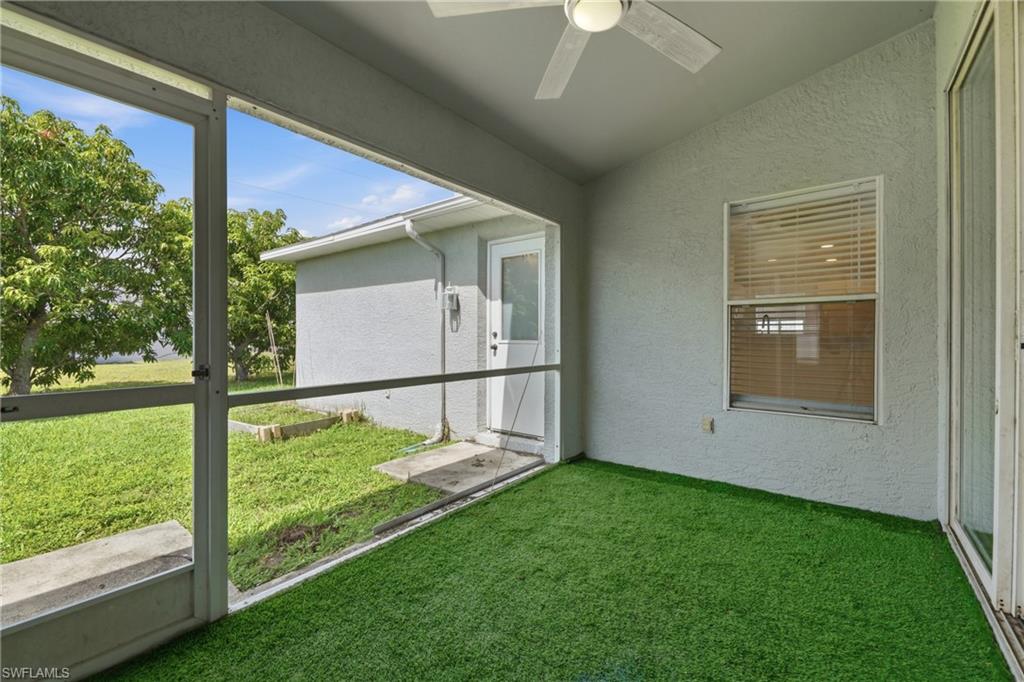 Screened outdoor area with textured walls, artificial turf flooring, and a ceiling fan