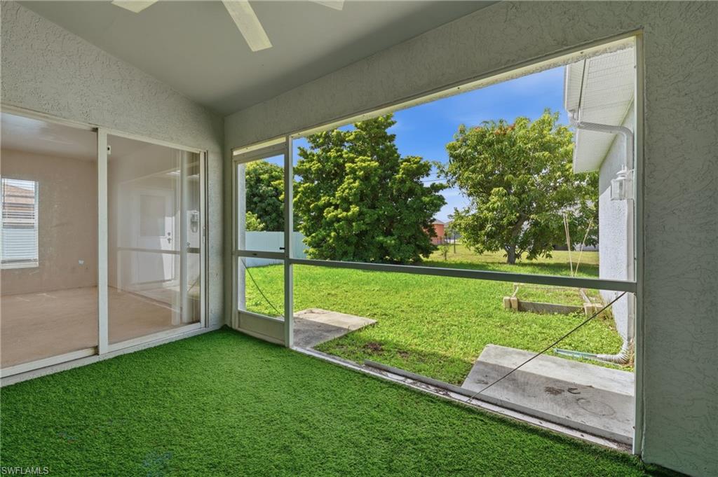 Screened patio with artificial turf flooring, ceiling fan, and sliding glass door