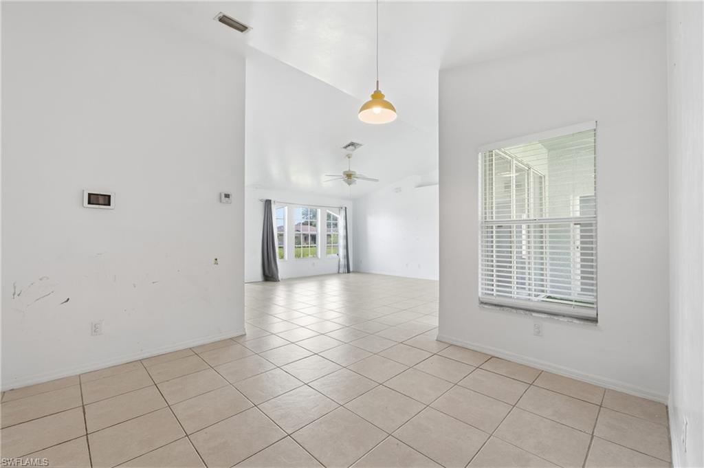 Vaulted ceiling, tiled flooring, window with blinds, pendant light fixture, ceiling fan