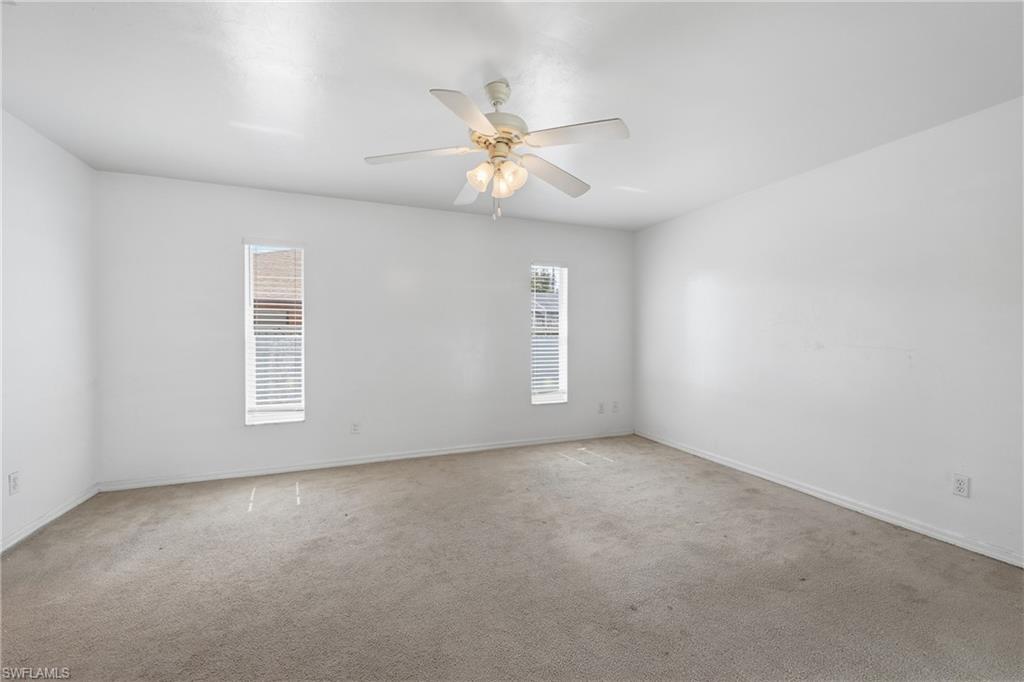 Recessed windows featuring blinds, ceiling fan with integrated lighting, and neutral carpeting