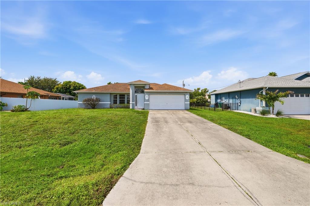 Single-story residence featuring a two-car garage, concrete driveway, and a manicured lawn