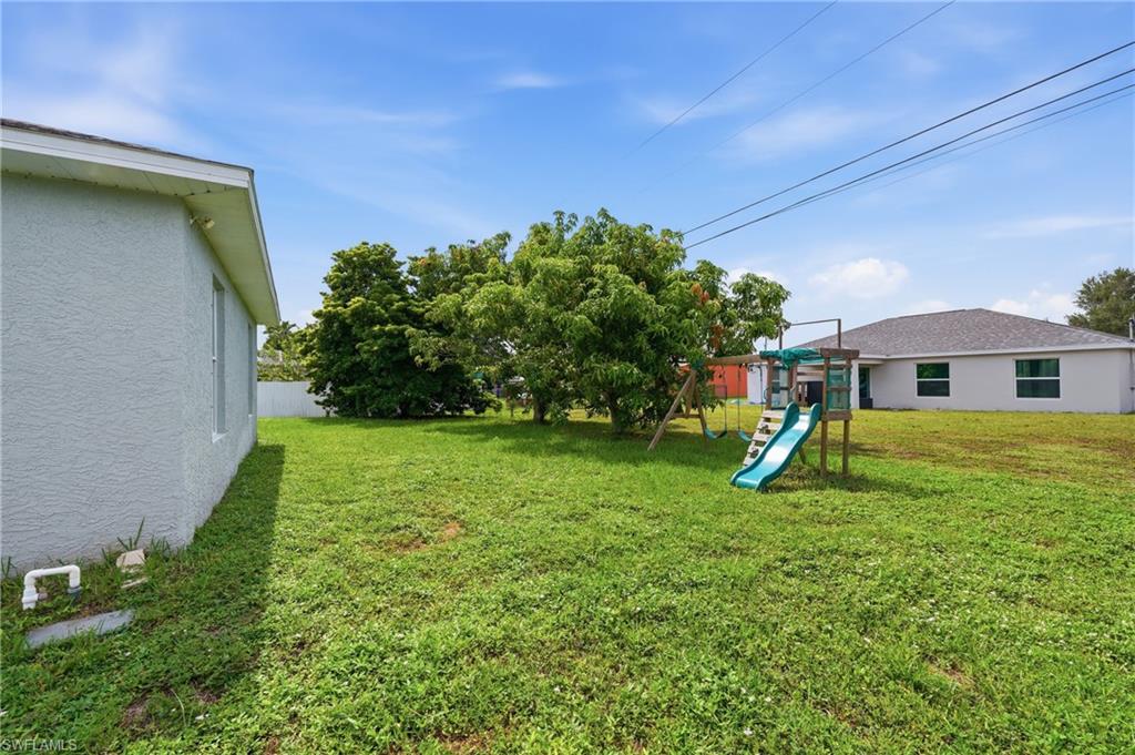 Expansive grassy yard with mature trees and a privacy fence