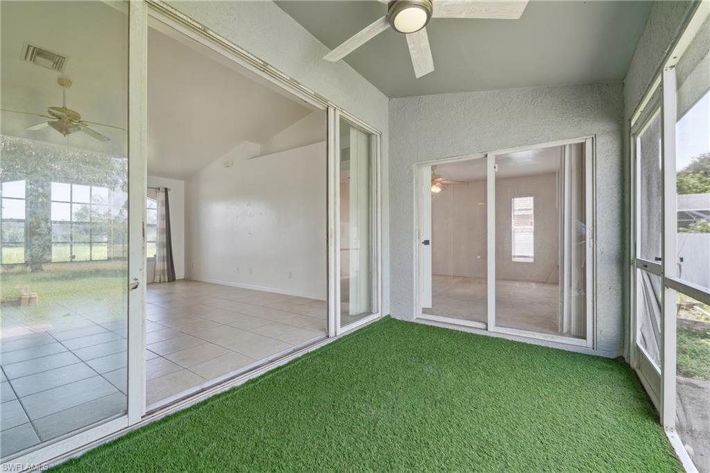 Screened-in patio with artificial turf flooring, featuring a ceiling fan, and multiple sets of sliding glass doors