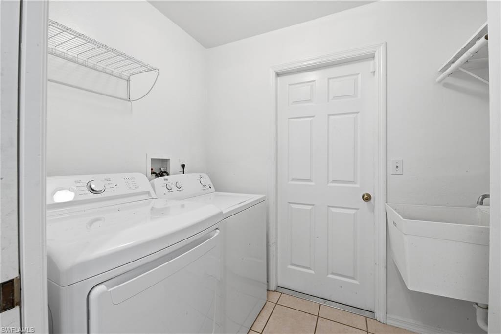 Utility room with a built-in wire shelf, tiled flooring, and a wall-mounted utility sink