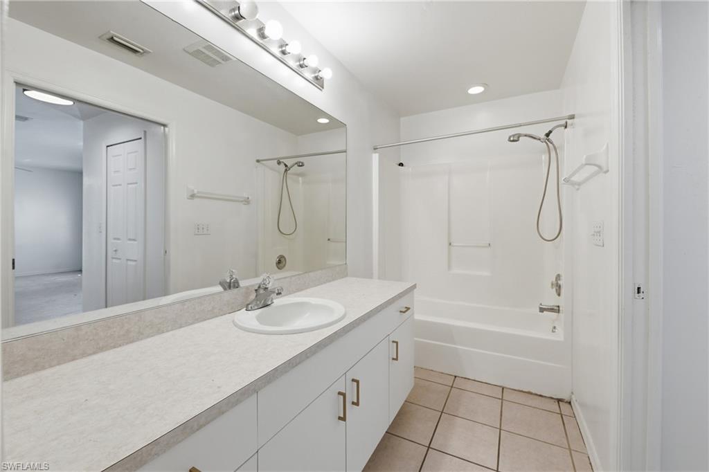 Vanity with an integrated sink, polished chrome faucet, and expansive wall-mounted mirror