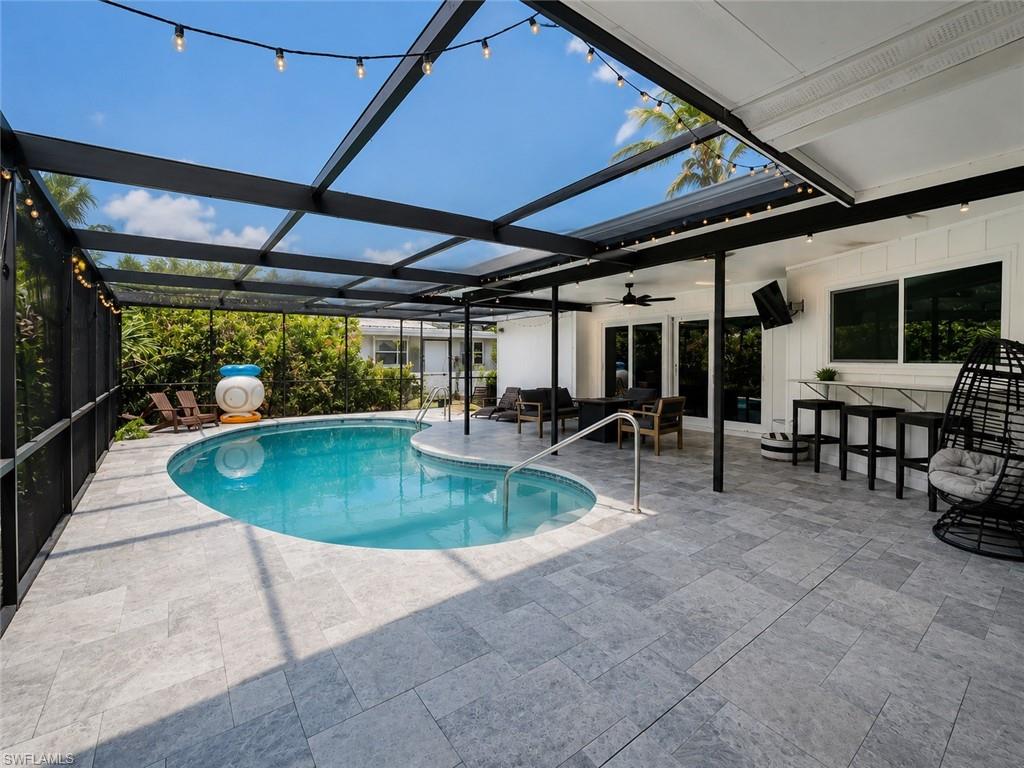 White exterior with decorative stone accents, mature palm trees, a dark brown garage door, and a paved driveway