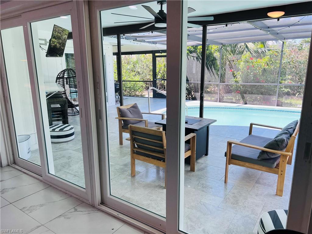 Sliding glass doors opening to a screened-in patio with a ceiling fan, light-toned tile flooring, and a swimming pool