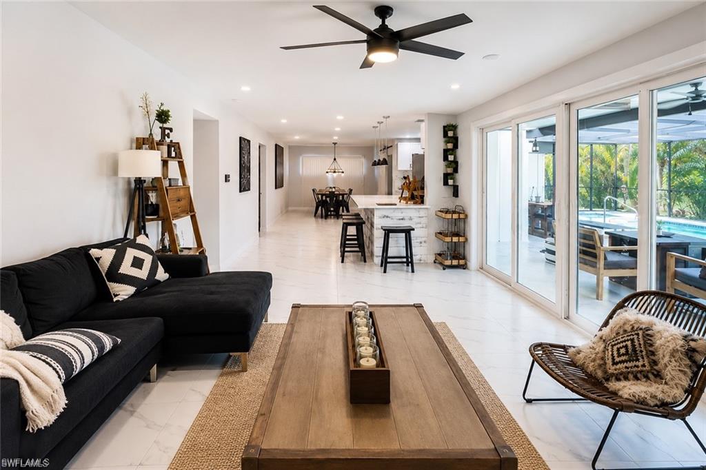 Screened-in outdoor living space with a freeform swimming pool, expansive tile patio, and covered dining area with built-in bar