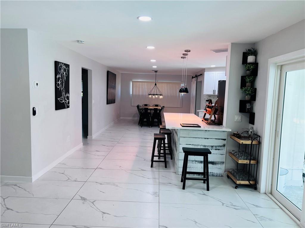 Spacious interior with large format tile flooring, modern linear chandelier, recessed lighting, and a white barn door