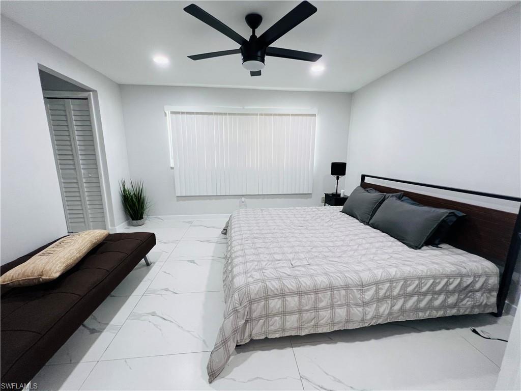 White tile flooring, recessed lighting, ceiling fan, window with blinds, and a white door with matte black hardware