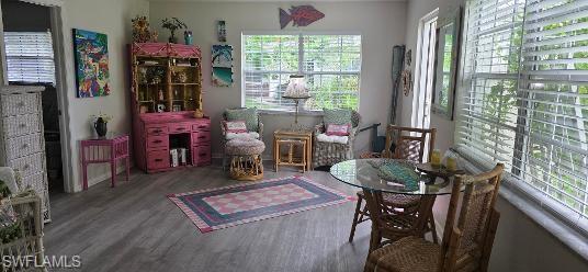 Spacious living area featuring wood-finish flooring, multiple windows with blinds, and white painted walls
