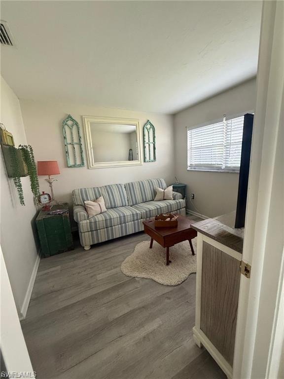 Bright room featuring wood-finish flooring, a neutral wall color, and a window with blinds