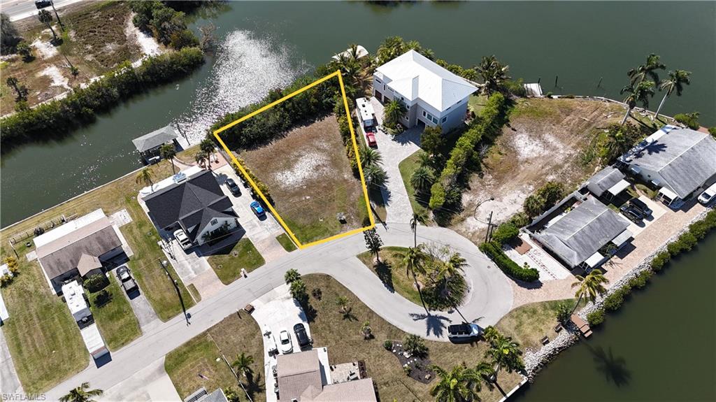 Aerial perspective of suburban area featuring a large body of water and property boundaries highlighted