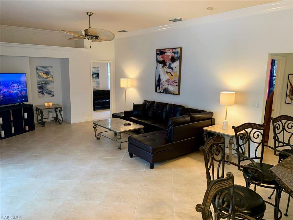 Living room with ceiling fan, crown molding, and light tile patterned floors
