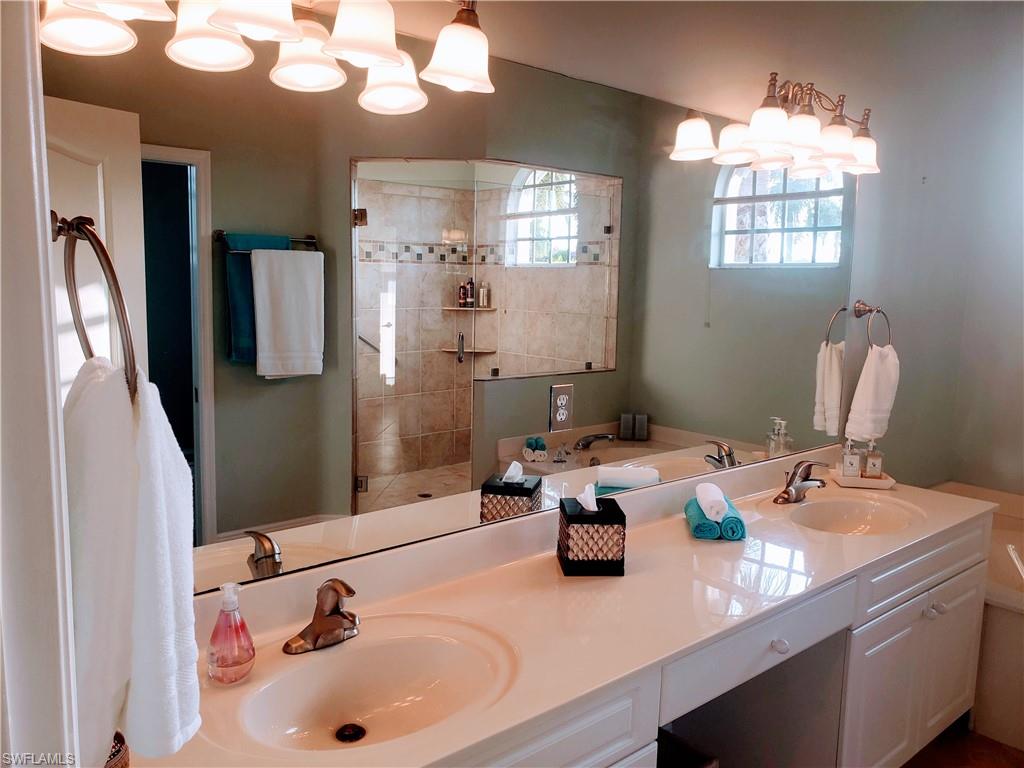 Bathroom with a tile shower, double sink vanity, and a chandelier