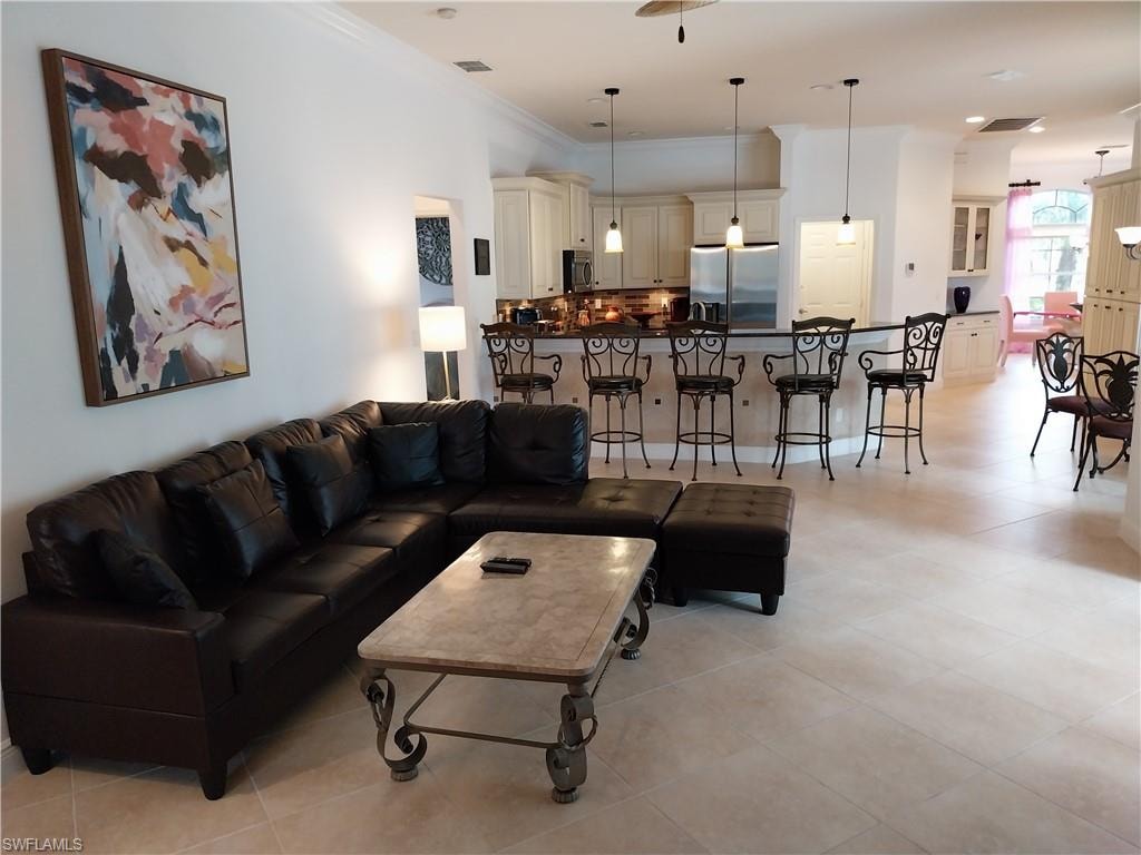 Living room with light tile patterned flooring and crown molding