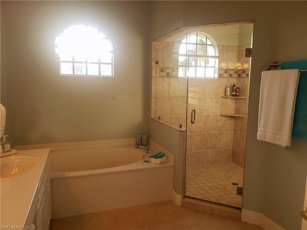 Bathroom with vanity, separate shower and tub, and tile patterned flooring